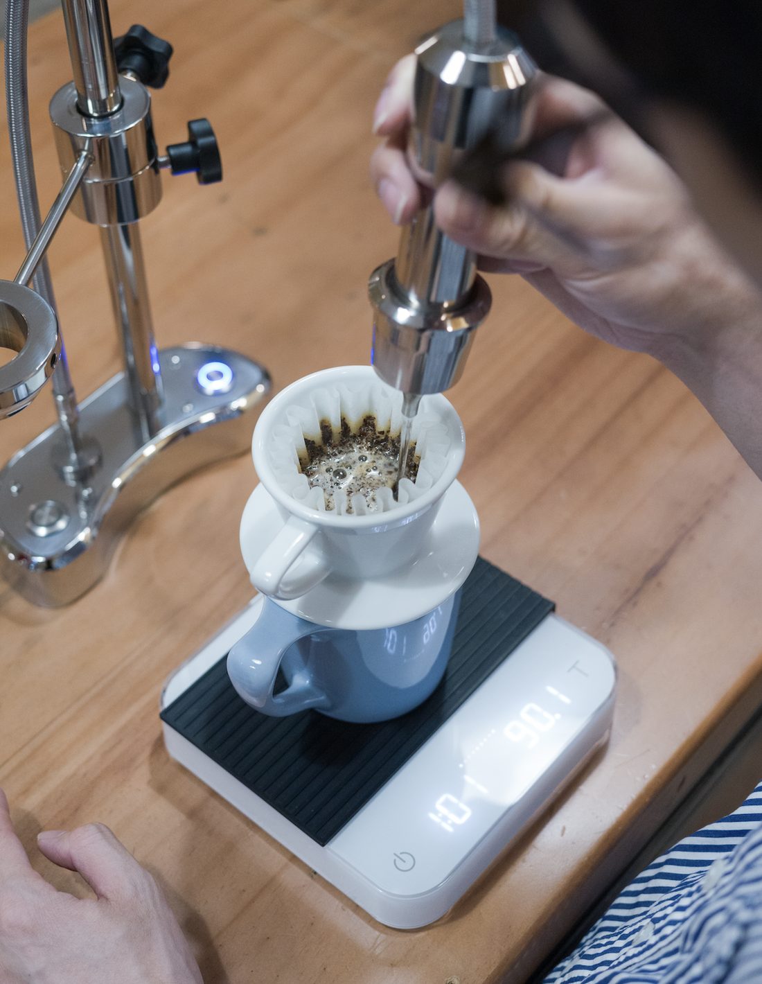 Rót nước ủ bloom lên lớp bột cà phê trong phễu Kalita Wave, đặt trên cân điện tử